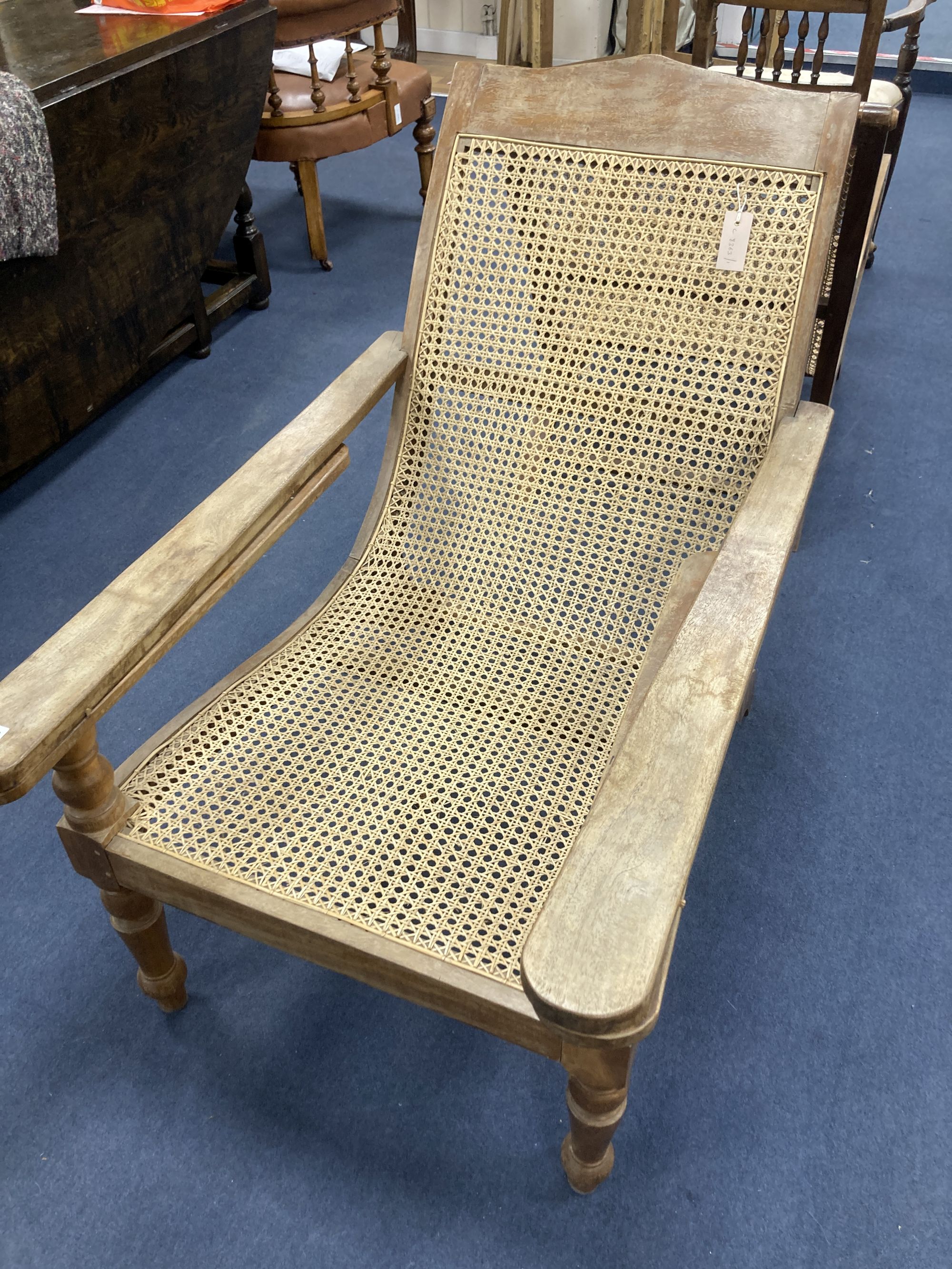 An early 20th century Anglo-Indian caned weathered plantation chair, width 66cm, depth 104cm, height 91cm